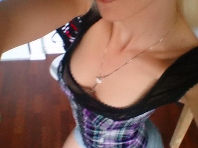 SwissMiss porte un haut à carreaux décolleté, avec une bordure en dentelle noire et un collier en argent, et montre ses seins. Sa peau est claire, et elle prend un selfie..