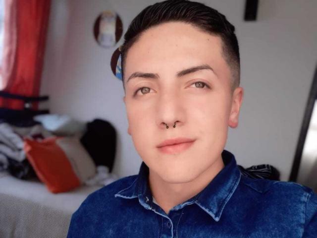 Anrey tem cabelo curto e escuro, olhos verdes e um piercing no nariz. Eles estão vestindo uma camisa de jeans azul, sorrindo levemente, e têm o rosto sem barba. As nádegas de Anrey não estão visíveis..