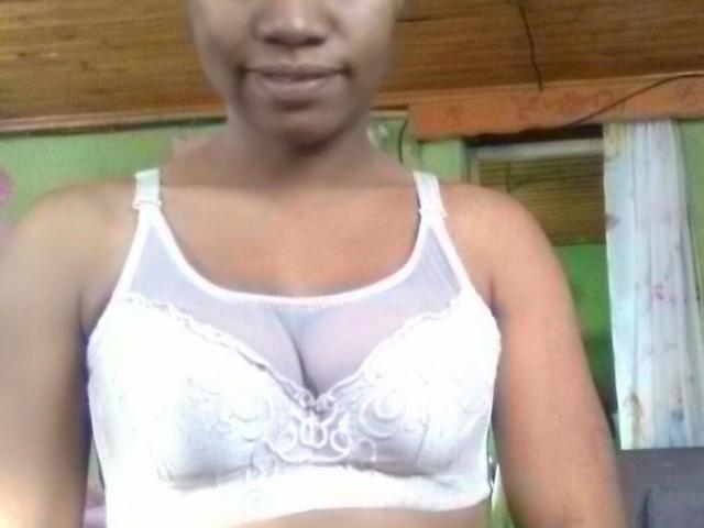 HoneyLovely, che indossa un reggiseno di pizzo bianco, mostrando i suoi piccoli, sodi e carini seni, con un leggero sorriso, in una stanza con soffitto in legno..
