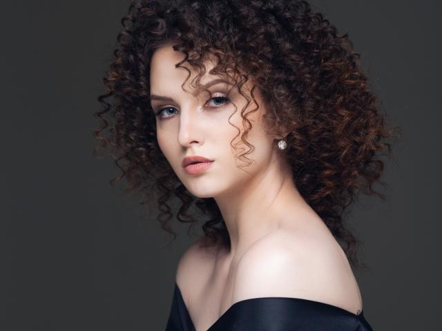 AriadnaShy ha i capelli castano ricci, la pelle chiara e gli occhi azzurri, indossa una maglietta nera con una spalla scoperta e un orecchino di diamanti. Il suo seno è parzialmente visibile..