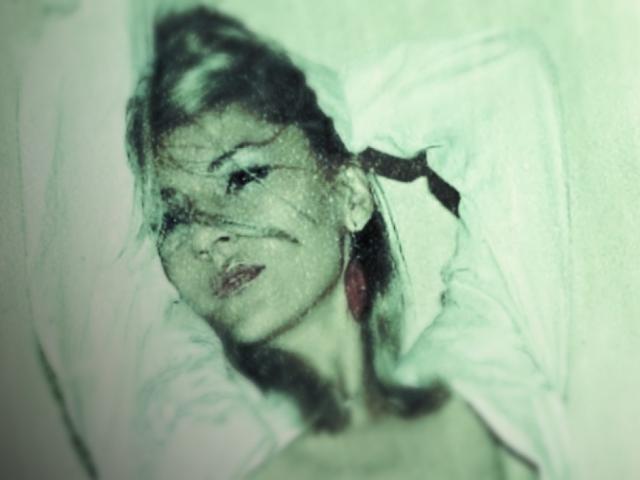 MissCelestine's face is partially obscured by dark strands, lying on a white pillow with her head tilted to the side, wearing a loose, white shirt. Her eyes are half-open.