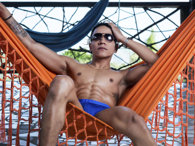MathewDell, sin camisa, musculoso, bronceado, vistiendo calzoncillos azules, gafas de sol negras, hamaca naranja, brazo tatuado, relajado, piernas separadas, manos en el pelo, al aire libre, de día, confiado, sexy..