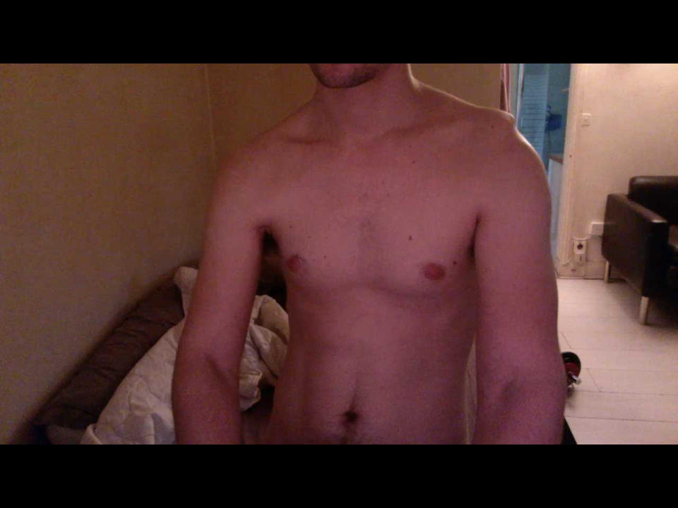O HeteroExhib é um homem sem camisa, com um corpo magro e sem pelos, pequenos mamilos e um umbigo ligeiramente visível. Seu rosto está parcialmente fora do quadro..