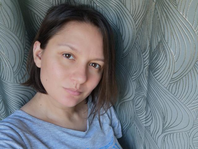 HayleyWendy tem pele clara, olhos castanhos e cabelo curto castanho. Ela está vestindo uma camisa cinza, com uma pequena perfuração no nariz e uma expressão neutra..