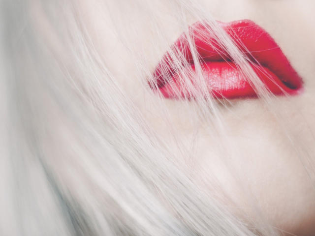 NycolSexy's glossy red lips are slightly parted, with white hair partially covering her face. Her full lips are the focus, highlighting her sexy, seductive look.