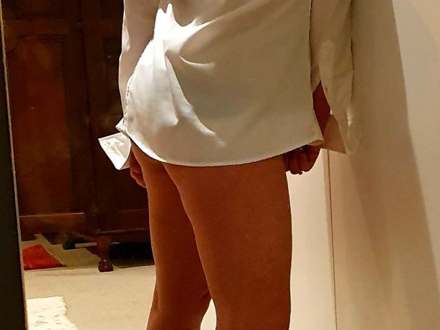 La camicia bianca di LustyLover copre i loro piccoli seni, lasciando scoperto il loro ventre abbronzato e le gambe. La loro mano destra è vicino all'inguine, mentre nell'altra mano tengono un panno bianco..