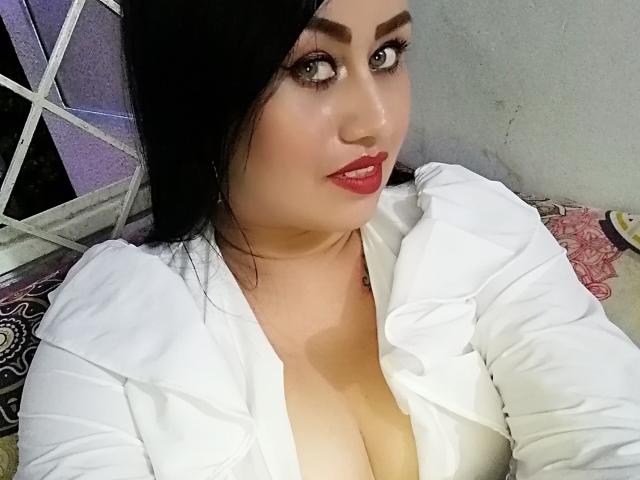 CathyCat, con capelli neri, rossetto rosso e camicia bianca che mette in mostra il décolleté, ha gli occhi azzurri e un leggero sorriso, e guarda verso la telecamera. Il seno è visibile, ma non vengono mostrate altre parti del corpo..