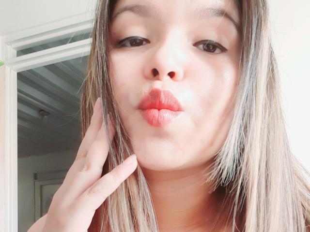 Myalewwis heeft volle, rode lippen, bruine ogen en lichtelijk rommelig blond haar, met een hand die haar wang aanraakt. Haar neus is klein en haar huid is licht..