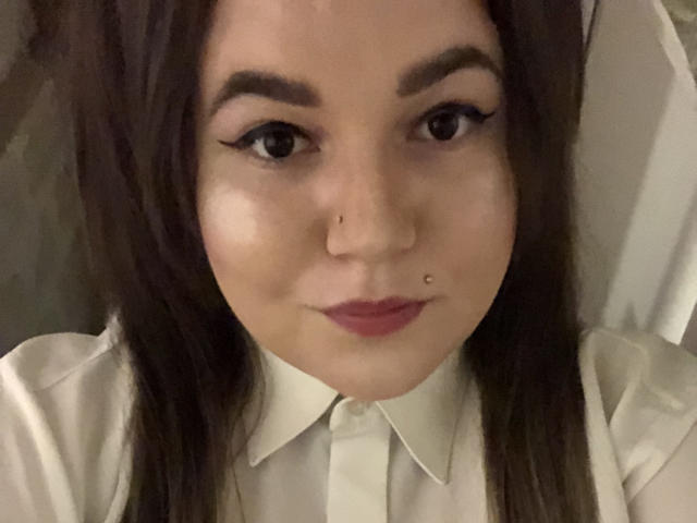 CherryXGirll hat dunkelbraunes Haar, eine Nasenpiercing, und leicht rosa Lippen, mit einem leichten Lächeln, und einen kleinen Nasenring in ihrem rechten Nasenloch, auf einem Selfie..