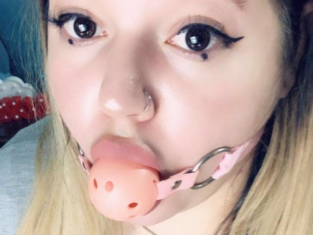 CherryXGirll hat dunkelbraunes Haar, hochgezogene Augenbrauen, schwarzen Eyeliner, ein kleines Nasenpiercing, einen Schönheitsfleck unter ihrem rechten Auge und trägt ein weißes Hemd mit Kragen..