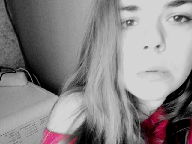 Das Gesicht eines sehr leidenschaftlichen Paares, leicht unscharf, mit langen, glatten, hellen Haaren, einem rosa, schulterfreien Oberteil und einem ernsten Gesichtsausdruck, auf einem Schwarz-Weiß-Foto mit rosa Akzenten..