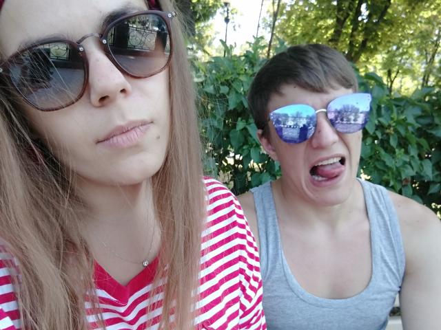 VeryPassionateCouple: mujer con camisa a rayas, pechos pequeños, cabello castaño, gafas de sol. MuyParejaApasionada: hombre con camiseta gris, cabello castaño corto, gafas de sol azules reflectantes, lengua afuera, hojas verdes..