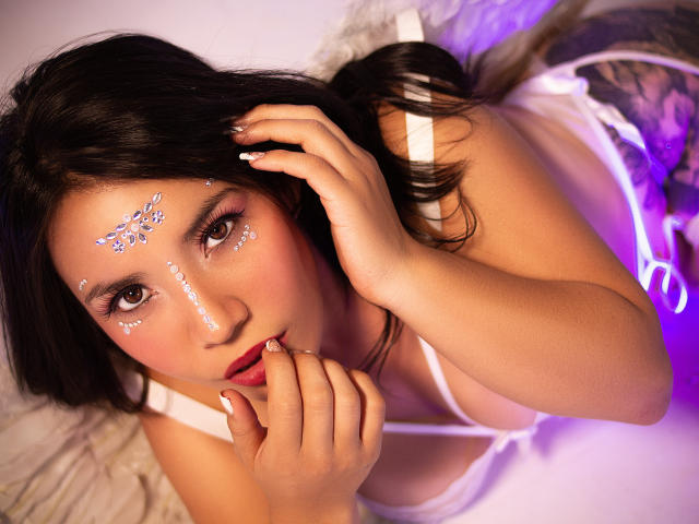 HelenRoss with dark hair, brown eyes, white face glitter, pink makeup, white lingerie, biting her finger, looking up, hand in hair, purple light, sexy, cute, soft, pink lips.