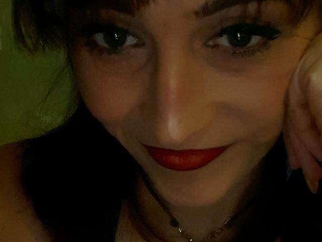 Xelenaxcbbs a les cheveux noirs et ondulés, des yeux verts et du rouge à lèvres. Elle sourit légèrement, avec un léger rougissement, et porte un bandeau noir ainsi qu'un collier avec un petit cœur..