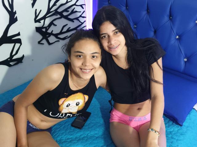 Two HotStarsForYou with cute smiles, black tank tops, and underwear. One has a chubby tan face, tiny tits, and a Pomeranian shirt. The other has a Latina face, small tits.