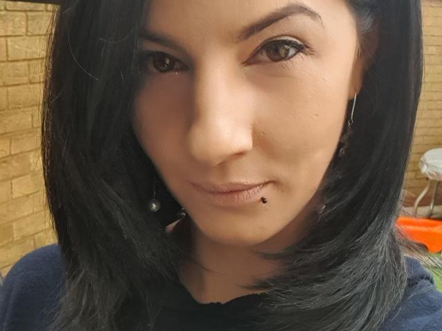 TonPlaisirDeReverBb ha i capelli neri, lunghi fino alle spalle, occhi marroni, un piercing al naso, un piercing al labbro con una pietra nera e indossa una maglietta scura..