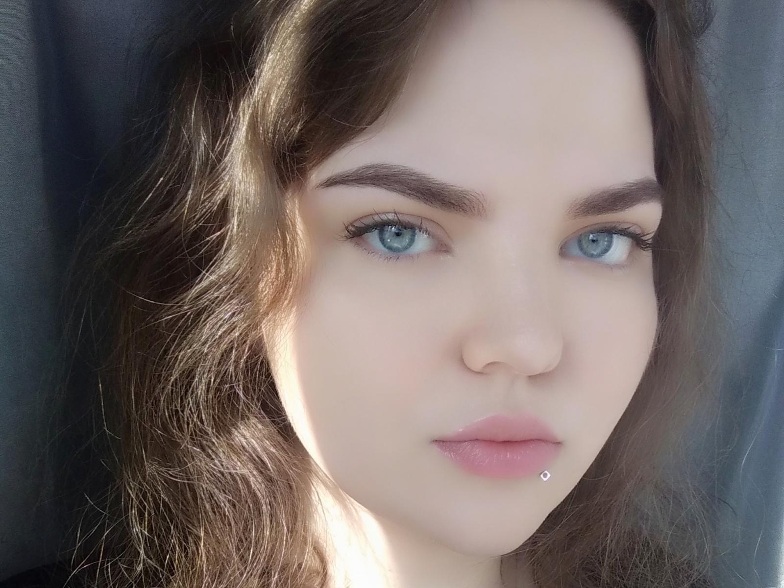 EishethZenunim heeft bleke huid, blauwe ogen, bruin golvend haar en een kleine zilveren lip piercing aan haar onderlip. Ze kijkt recht in de camera met een neutrale uitdrukking..