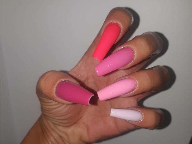 ExquisDunya's hand with long, glossy, manicured nails in pink, red, and white. Boob-sized pink nails, finger-sized red and white nails, all shiny and slightly curved.