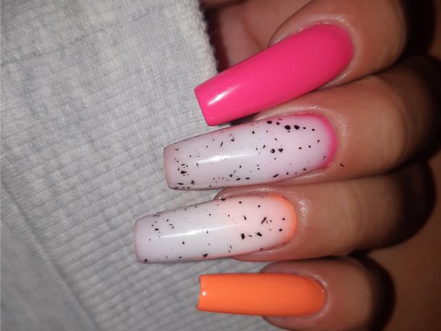 Les ongles d'ExquisDunya sont peints avec du vernis rose vif, blanc avec des taches noires et orange. Ses longs ongles brillants sont super mignons et sexy..
