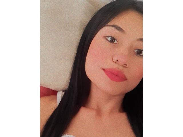 LolyFunX has straight black hair, light skin, and pink lips. She's looking at the camera with a slight smile, and her small nose is pierced. Her tits are not visible.