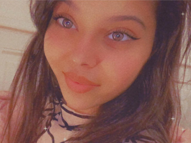 Bellefrancaise69 tiene ojos marrones, delineador de ojos negro y una sonrisa encantadora con labios rosados. Tiene el cabello largo y castaño, y lleva un collar negro con un diseño de encaje..