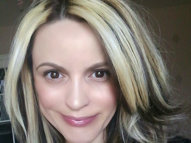 FlightLight tiene cabello rubio y castaño, ojos marrones y una sonrisa sutil con labios rosados. Su piel es clara y está mirando directamente a la cámara..