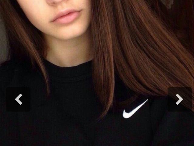 Il viso di JosefineDarkfeel, con i capelli castani e lisci che le coprono il lato destro, indossa una maglietta nera Nike, mostrando le sue labbra rosa, leggermente dischiuse, e un piccolo logo Nike bianco..