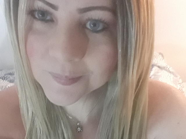 SaraSupreme ha i capelli biondi, gli occhi azzurri e un viso carino con il rossetto rosa. Le sue spalle sono scoperte e indossa una collana con un piccolo fiore..