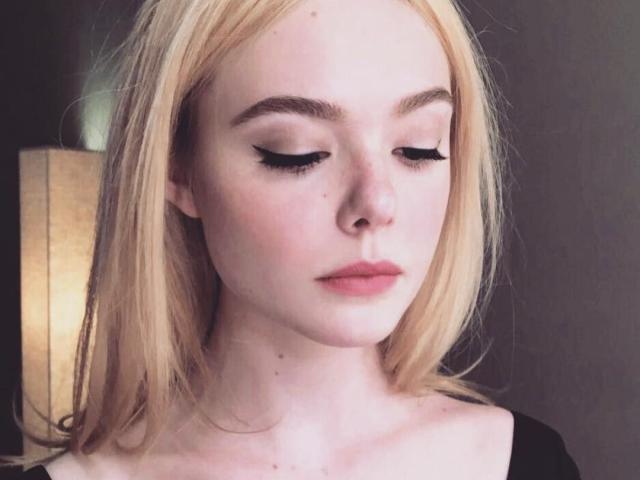 AnnabelPower ha la pelle chiara, i capelli biondi e l'eyeliner nero. Ha gli occhi chiusi e indossa il rossetto rosa. Sta guardando in basso con un'espressione neutra..
