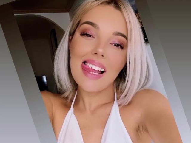 JuliCandy with blonde bob, pink eyeshadow, white halter top, sticking out tongue, showing off pearly white teeth, and a cute smile.