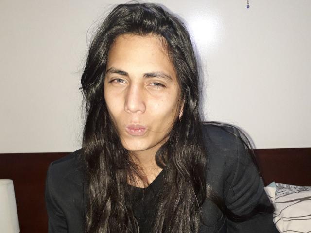 Igorendon, con cabello negro largo, labios fruncidos y una expresión ligeramente seria, vistiendo una camisa negra, mirando directamente a la cámara..