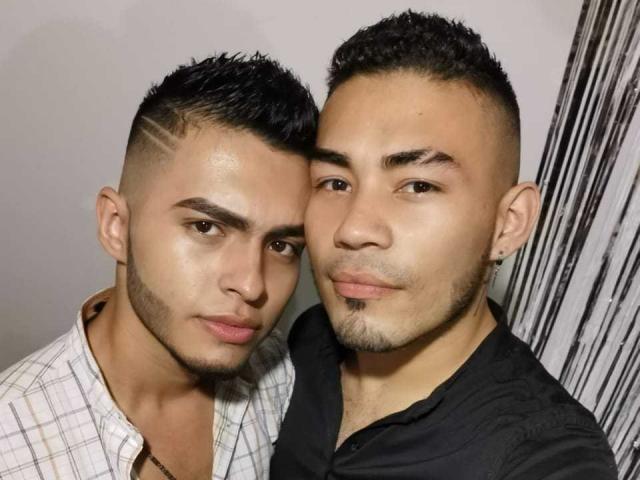 Andrew e Matthew têm rostos bonitos, com um pequeno piercing no nariz, cabelo preto curto e barba clara. Matthew tem um penteado semelhante, uma camisa preta e um brinco..