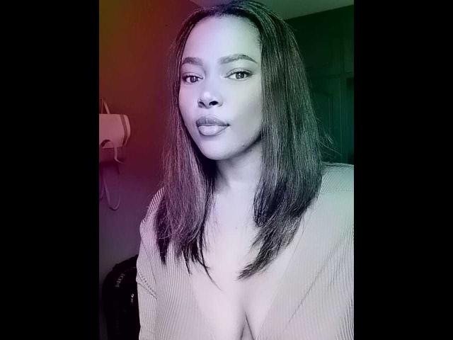 EmiraHot has medium brown skin, straight black hair, and small tits. She's wearing a low-cut, beige top, looking at the camera with a slight smile.