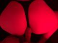GingerLiam's ass, red-lit, with a circumcised, erect penis, slightly visible between their butt cheeks, wearing black underwear, in a dark, intimate setting.
