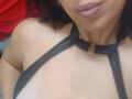 LauraSin with dark hair, wearing a black halter top with a ring at the collar, showing her tan skin and pouty pink lips, upper chest and collar visible.