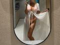 SandraSwweet in a sheer white robe, revealing her pink panties and tits, holding the robe open, showing her ass and standing in front of a mirror.