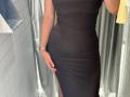 MargoFun wearing a tight, black, sleeveless dress with a thigh-high slit, showing her curvy, brown-skinned, slim-ass, and wearing a silver wristwatch.