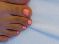 MoniqueBliss's toes with pink nail polish, slightly shiny, on a blue textured towel. Her skin is a medium brown tone, and her toes are neatly aligned.