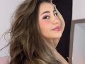 LorensDouce has long brown hair, pink eyeliner, and glossy pink lips. She's looking over her shoulder with a slight smile. Her tits are not visible.