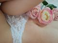 AmeliaMaiv's lace white panties, showing her soft, pale skin, with pink roses resting on her lower belly and a hint of her butt. Her panties are slightly pulled down.