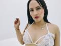 EmhilyDiaz with black hair, red lipstick, white lace bra showing small tits, silver necklace, holding bloody hand, wearing hoop earrings, light skin, looking at camera.