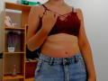 Steisii with tan lines, red lace bra, and blue jeans, holding bra strap, showing her tits and flat stomach. Her hand's on her right tit.