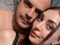 LettieMaddy's face is next to a bald man's with a beard, both have tan skin and brown eyes, she has dark brown hair, he's shirtless with a silver necklace.