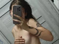 MathaDernier taking a selfie with a phone, covering her tits with one hand, showing snake tattoos on her right arm, in a bathroom. Her hair is wet.