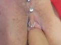French: La vulve de Shanna, avec un piercing en forme d'anneau en argent et une bille en argent sur le prépuce du clitoris, étant pénétrée par un pénis circoncis, érectile et de peau claire..