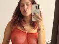 ValeryScot with curly red hair, puffy lips, wearing a red mesh top, showing her tits, holding a phone with red nails, and a gold necklace. Mirror selfie.