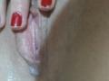 Kelliy69's pink pussy with visible labia being gently spread by fingers with red painted nails. Her skin is slightly shiny and textured.