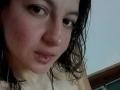 ArianaBlonde's face with wet, dark blonde hair, slightly parted pink lips, and a small lip piercing. She has light skin, brown eyes, and a subtle blush on her cheeks.