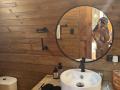 MajoJones stands nude in front of a mirror, showing her bare tits and ass. She holds a phone, reflecting in a round mirror above a wooden sink.