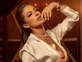 KarlaSoto with dark hair, wearing a white shirt open to show her tits, gold necklace, and watch, hand near face, warm light, slightly parted lips, seductive expression.